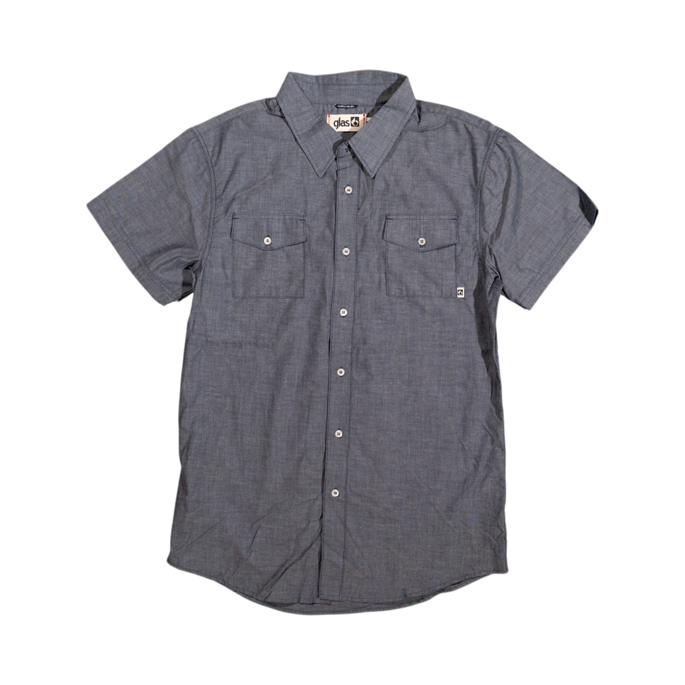 Glas Apparel Protrero short sleeve button-down shirt in blue chambray with dual chest pockets on wood floor