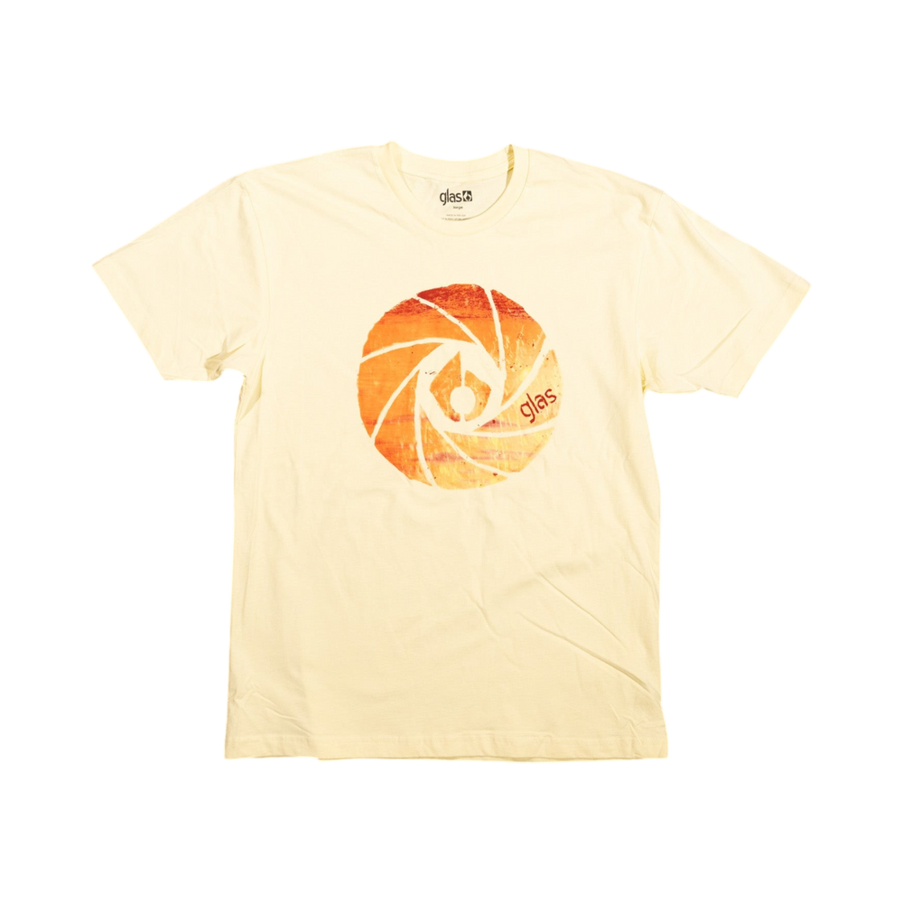 Glas Apparel Shutter Sun Tee in pale yellow with a circular camera shutter graphic print on the chest.